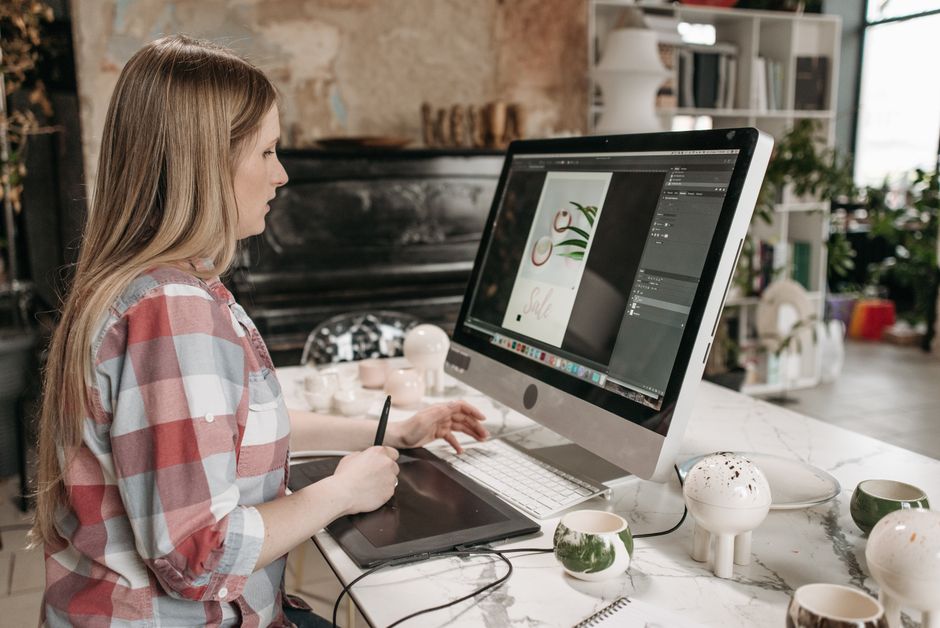 Can Laser Printers Print Color? The Ultimate Design and Color Guide 3 A graphic designer comparing a digital layout on a calibrated monitor with a printed proof sheet from a color laser printer
